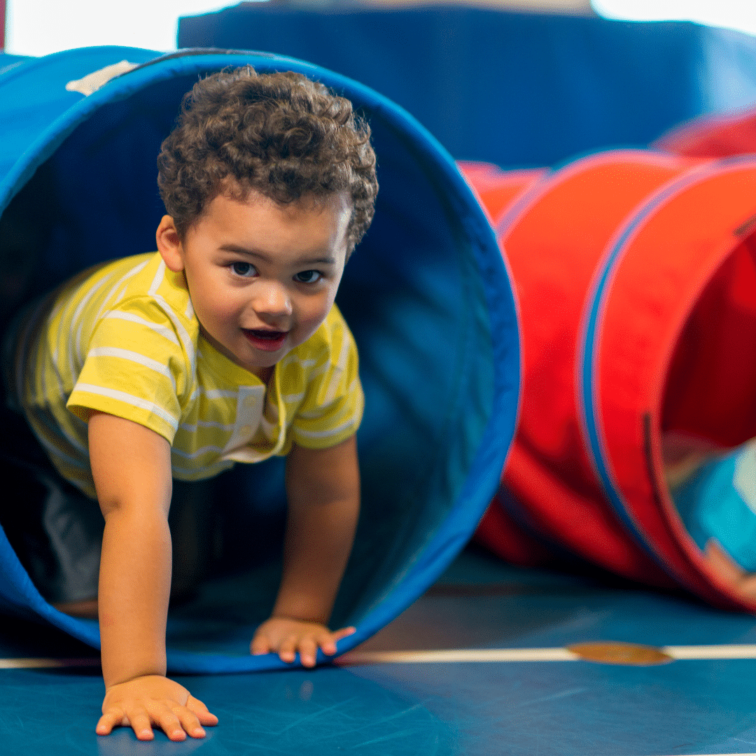 child playing inside a toy fabric tunnel