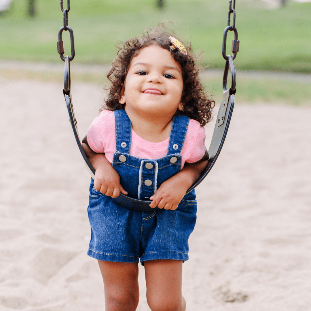 happy little girl playing on a swing set